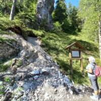 Pilger vor Tafel in Waldweg