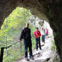 Pilgergruppe der Mariazell-Wallfahrt im Wald mit kuzrer Felshöhle/-durchgang davor